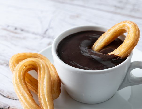 Traditional Spanish churros with hot chocolate breakfast on wooden table